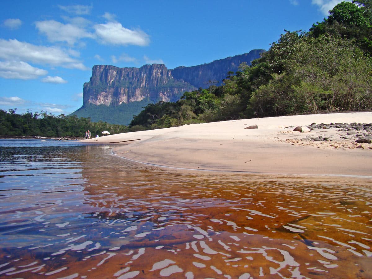 Playa de aguas oscuras frente a un tepuy en Canaima